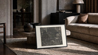 Winged demon Lucifer in underworld cavern print in a slim black frame leaning on a travertine coffee table