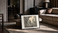 Crouching giant and two robed figures print in a slim black frame leaning on a travertine coffee table
