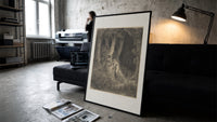 Robed man in dark forest print in a slim black frame leaning on a dark sofa in a concrete print studio