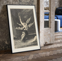 winged demon carrying nude figure print in a black frame leaning beside a vintage door on parquet