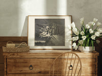 winged demons and two robed figures print in an oak frame on a farmhouse dresser beside white tulips