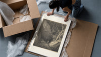 Two figures walking through dark forest framed print being unpacked from protective bubble wrap and a box