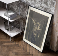 Winged monster carrying two figures poster in a black frame leaning beside a shelf in a raw-plaster loft