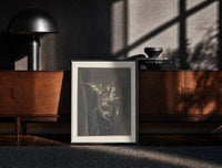 Black-framed Winged monster carrying two figures print on a moody console with designer coffee-table books
