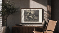 Boatman ferrying souls across river print in a wood frame above a fluted sideboard beside an olive tree