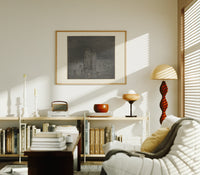 Two robed figures among buried heads print in an oak frame above a mid-century book console with a vintage radio