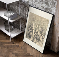 Faces in gnarled bare trees poster in a black frame leaning beside a shelf in a raw-plaster loft