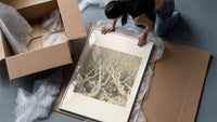 Faces in gnarled bare trees framed print being unpacked from protective bubble wrap and a box