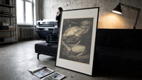 Chained muscular giant with crown print in a slim black frame leaning on a dark sofa in a concrete print studio