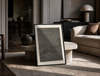 Two robed figures under starry sky print in a black frame leaning on a travertine table in a sunlit lounge