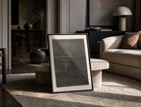 Two robed figures on cliff at night print in a black frame leaning on a travertine table in a sunlit lounge