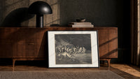 Charon ferrying damned souls print in a black frame leaning against a walnut console in lamplight