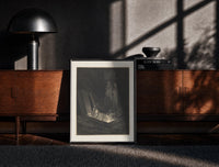Black-framed Figure rising from tomb in hell print on a moody console with designer coffee-table books