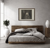 Starving prisoners in dungeon print in a dark wood frame above a rattan bed on a plaster wall