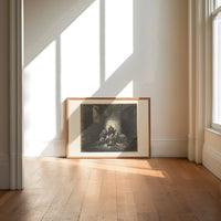 Starving prisoners in dungeon print in an oak frame on a sunlit wood floor beneath tall window light