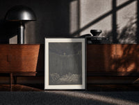Black-framed Two figures overlooking pit of souls print on a moody console with designer coffee-table books