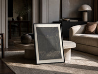 Two figures overlooking pit of souls print in a black frame leaning on a travertine table in a sunlit lounge