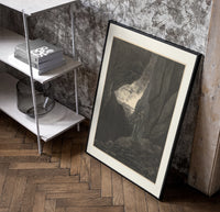 Two robed figures in rocky gorge poster in a black frame leaning beside a shelf in a raw-plaster loft