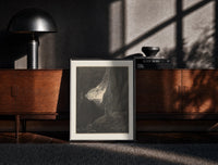 Black-framed Two robed figures in rocky gorge print on a moody console with designer coffee-table books