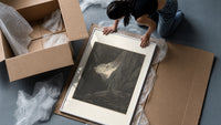 Two robed figures in rocky gorge framed print being unpacked from protective bubble wrap and a box