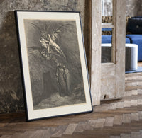 Winged demons flying above two robed figures print in a black frame leaning beside a vintage door on parquet