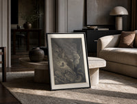Two figures facing a winged monster print in a black frame leaning on a travertine table in a sunlit lounge