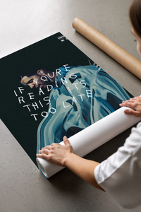 Woman unrolling a black and white Drake poster print across a concrete floor