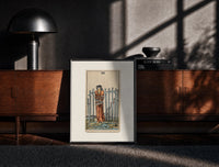 Black-framed Blindfolded bound woman among swords print on a moody console with designer coffee-table books