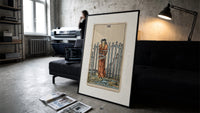 Blindfolded bound woman among swords print in a slim black frame leaning on a dark sofa in a concrete print studio