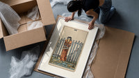 Blindfolded bound woman among swords framed print being unpacked from protective bubble wrap and a box