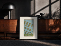 Black-framed Eight flying wands over landscape print on a moody console with designer coffee-table books