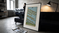 Eight flying wands over landscape print in a slim black frame leaning on a dark sofa in a concrete print studio