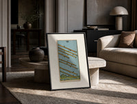 Eight flying wands over landscape print in a black frame leaning on a travertine table in a sunlit lounge