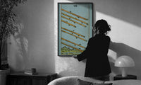 Eight of Wands print in a slim black frame being hung on a sunlit wall in a monochrome room