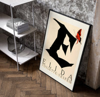 Butterfly on giant letter E poster in a black frame leaning beside a shelf in a raw-plaster loft