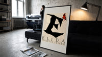 Butterfly on giant letter E print in a slim black frame leaning on a dark sofa in a concrete print studio