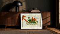 Christmas sled with holly and ribbon print in a black frame leaning against a walnut console in lamplight