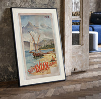 Sailboats on alpine lake bay print in a black frame leaning beside a vintage door on parquet