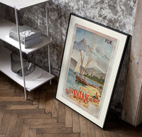 Sailboats on alpine lake bay poster in a black frame leaning beside a shelf in a raw-plaster loft