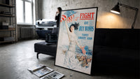 Fight or Buy Bonds Third Liberty Loan print in a black frame leaning against a dark sofa in a concrete studio