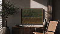 Figures on a beach by sea print in a wood frame above a fluted sideboard beside an olive tree