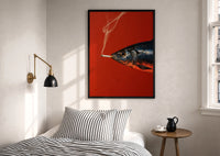 Fish Smoking a Cigarette print in a black frame above a bed with striped linens, a brass wall lamp and a sunlit window
