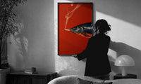 Fish Smoking a Cigarette print in a slim black frame being hung on a sunlit wall in a monochrome room