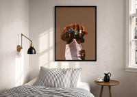 Fist with a Blue Gemstone Ring print in a black frame above a bed with striped linens, a brass wall lamp and a sunlit window
