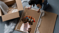 Fist with a Blue Gemstone Ring framed print being unpacked from protective bubble wrap and a box