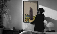 Five of Cups print in a slim black frame being hung on a sunlit wall in a monochrome room