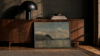 Coastal fjord landscape with headland print in a black frame leaning against a walnut console in lamplight