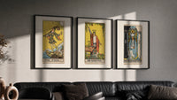 Three 1909 tarot cards triptych in three black frames on a grey wall above a leather sofa