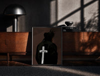 Black-framed Forgiven Cross Hoodie print on the floor in front of a dark wooden console
