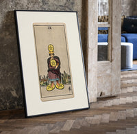 Man clutching gold pentacle coins print in a black frame leaning beside a vintage door on parquet
